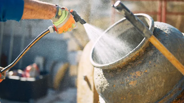 man cleans concrete mixer with a high-pressure sprayer