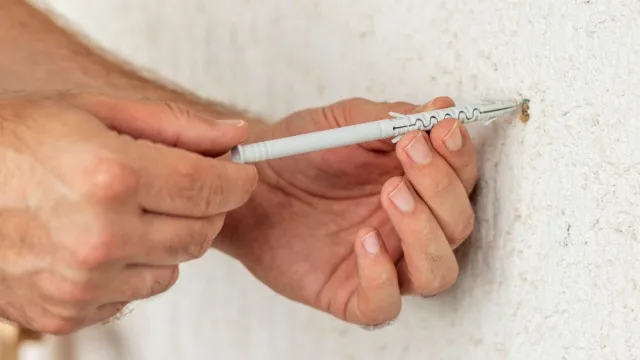 man pushes plug into drill hole