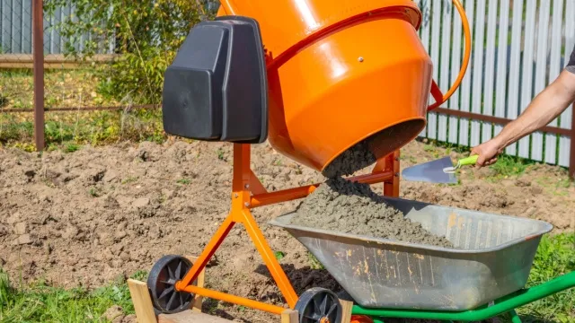 man empties concrete mixer into wheelbarrow