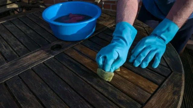 man cleaning wooden garden table