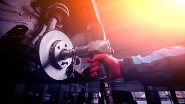 car mechanic working with pneumatic impact wrench