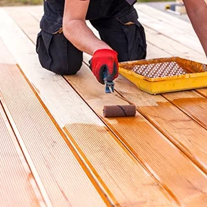 man stains deck with roller