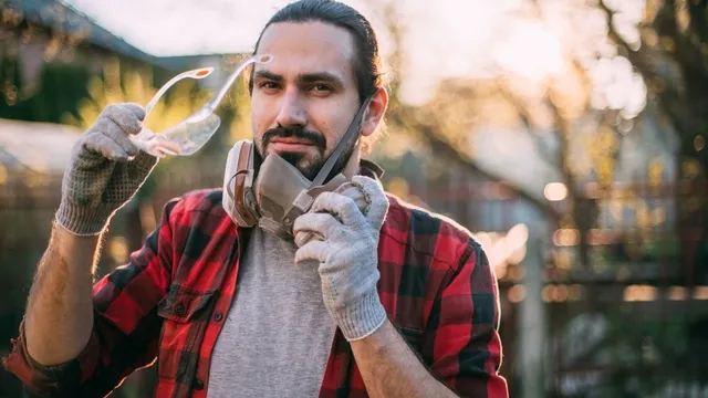 man met veiligheidsbril, handschoenen en stofmasker